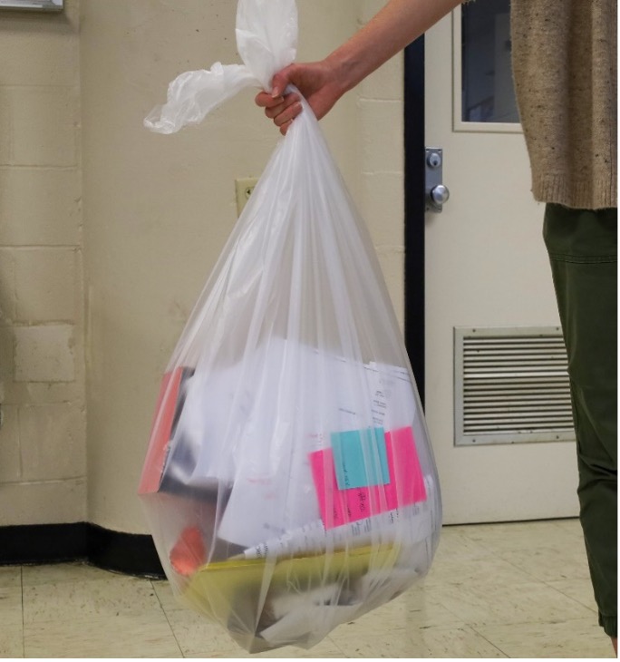 a person holding a clear bag that is filled with recyclables