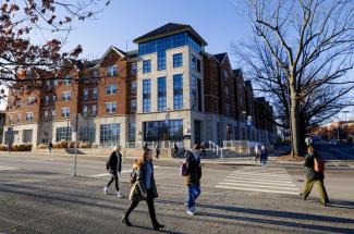 Students pass along the sidewalk in front of the Lewis Honors College.