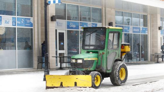 Photo of worker clearing snow and ice on campus.