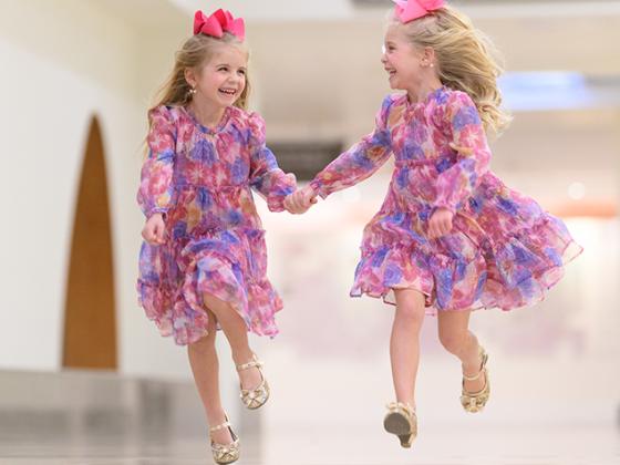 Twin girls skipping down a hallway